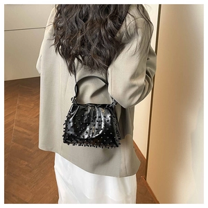 Detail of a black beaded bucket bag with pearls and glossy finish shown on model