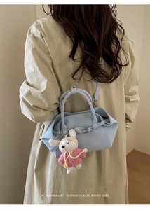 Détail du sac seau bleu clair avec un pendentif lapin blanc et boucle en métal argenté