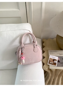 Détail du sac à main en cuir rose avec logo embossé et breloque champignon