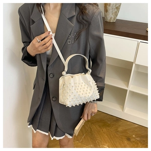 Close-up of stylish white bucket bag featuring elegant pearl matrix decor and drawstring