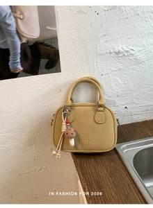 Gros plan du sac en cuir PU jaune avec logo embossé et détail de charm champignon