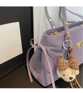Close-up of lavender purple lychee grain bag with gold hardware and a cute teddy bear charm