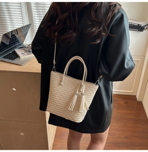 Détail du sac seau crème avec motif gaufré en éventail et breloque à double gland