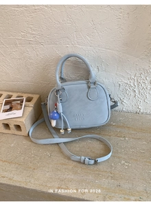 Gros plan du mini sac bleu clair avec relief MUT ING et détail de pendentif champignon