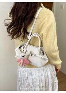 Détail d'un sac seau blanc avec breloque lapin porté par un mannequin en studio