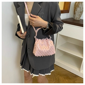Detail of pink pearl bucket bag featuring glossy finish and drawstring closure