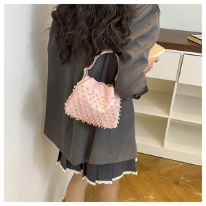 Detail shot of light pink pearl bucket bag shown on a model in a stylish indoor setting
