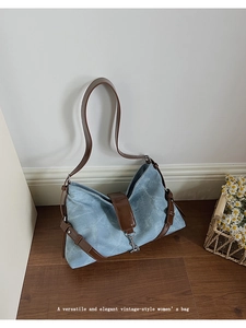 Detail view of vintage denim shoulder bag with brown leather straps on wood floor