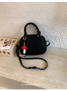 Détail du sac rétro noir avec logo MUTING, breloque champignon et boucle argentée
