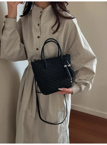 Détail du sac seau plissé noir avec glands décoratifs et longue bandoulière
