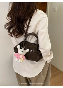 Sac à main rétro marron minimaliste avec pendentif lapin porté par un mannequin