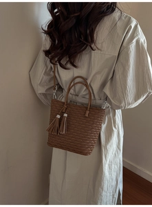 Gros plan d'un sac seau marron gaufré avec pompons porté par un mannequin femme