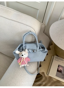 Détail du sac à main en cuir bleu clair avec breloque lapin sur un canapé crème confortable