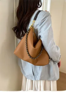 Brown lychee leather hobo bag with gold chain strap shown on model in blue blazer