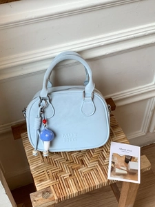 Petit sac carré vintage bleu clair avec breloque champignon sur un tabouret en rotin