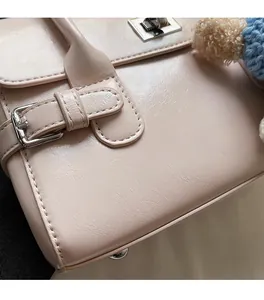 Detail of light beige faux leather handbag with silver metal buckle and litchi texture