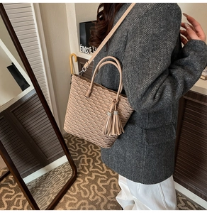 Vue détaillée du sac seau plissé beige avec pompon décoratif et anses rondes élégantes