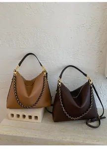 Detail of hobo bags in brown and coffee lychee pattern leather with golden chain accents