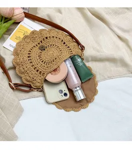 Detail of hollow woven straw saddle bag with magnetic closure and spacious interior