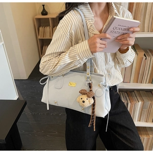 Detail of light blue tote bag with gold metal plate and teddy bear charm accessory