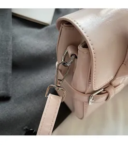 Detailed macro shot showing silver metallic buckles and textured pink leather on the handbag