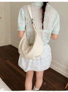 Detail der cremeweißen Hobo-Tasche aus Kunstleder mit Lychee-Narbung und Gurt