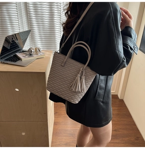 Détail d'un sac seau grège avec surpiqûres en éventail et pompon cristal porté