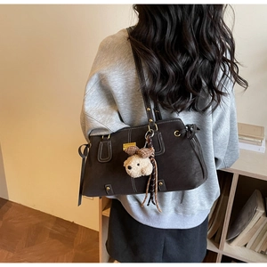 Back view of brown matte tote bag with shoulder straps and plush bear charm