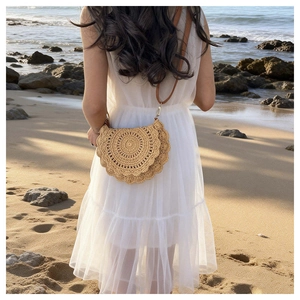 Detail of bohemian semi-circle woven straw saddle bag worn on a sunset beach