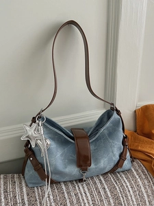 Retro denim shoulder bag with brown leather straps and star charms on tweed surface