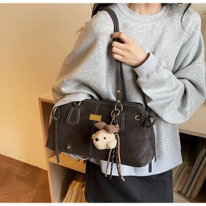 Detail of dark brown tote bag with side drawstring and cute plush dog charm accessory
