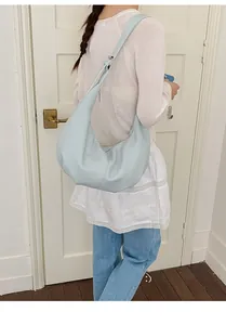 Model trägt eine hellblaue halbmondförmige Hobo-Tasche mit verstellbarem Riemen im Detail
