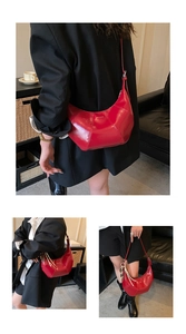 Detail view of bright red leather crescent bag with logo and reinforced stitching
