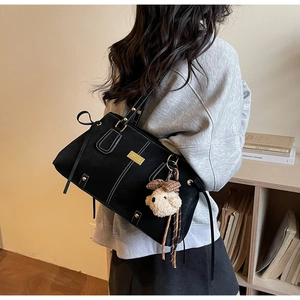 Close-up of black canvas tote bag with contrast stitching and teddy bear charm