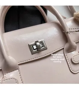 Close-up of silver metal twist lock on a light pink textured leather handbag with plush charm