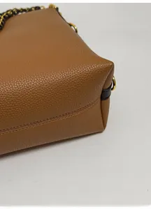 Detailed close-up of a brown textured leather tote bag bottom with reinforced base design