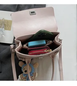 Detail view of pink leather handbag with multi-compartment interior and silver turn-lock