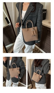 Détail d'un sac seau kaki tressé avec pompon en cuir et bandoulière amovible élégante