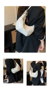 Detail view of a white crescent shoulder bag with vintage leather finish and stitch patterns