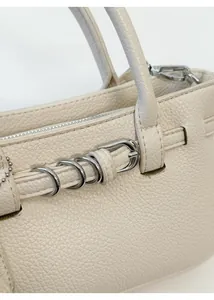 Detail der cremeweißen Lederstruktur und silbernen Metallringe an einer Handtasche