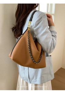 Detail of caramel brown litchi grain leather hobo bag with woven gold chain strap