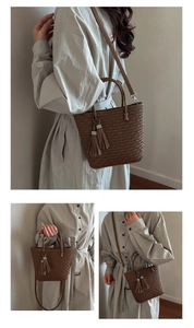 Détail d'un sac seau marron foncé avec pompon élégant et bandoulière amovible