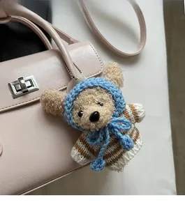 Detail of a handmade crochet bear keychain hanging on a stylish vintage leather handbag