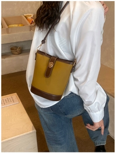 Modella indossa borsa a secchiello retrò in pelle zenzero con bordo marrone e fibbia d'oro