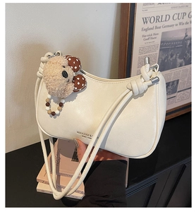 Detailed shot of cream-colored shoulder bag with cute teddy bear charm and colorful beads