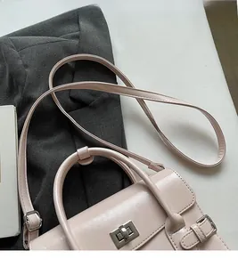 Detail of a pink vintage-style handbag with silver twist lock and smooth leather texture