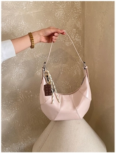 Detail of pink crescent bag with radial stitching and chocolate ribbon charm accessory