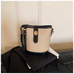 Dettaglio borsa a secchiello in pelle beige con finiture nere e chiusura dorata
