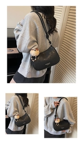 Detail of black crescent shoulder bag with knot strap and plush bear pearl keychain