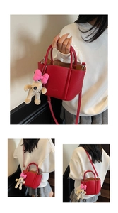Detail view of red lychee grain leather bucket bag with cute dog charm and shoulder strap